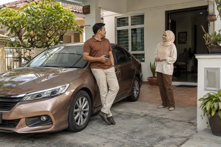 Pelanggan dengan kantung kunci di sebelah kereta yang diparkir di kediaman
